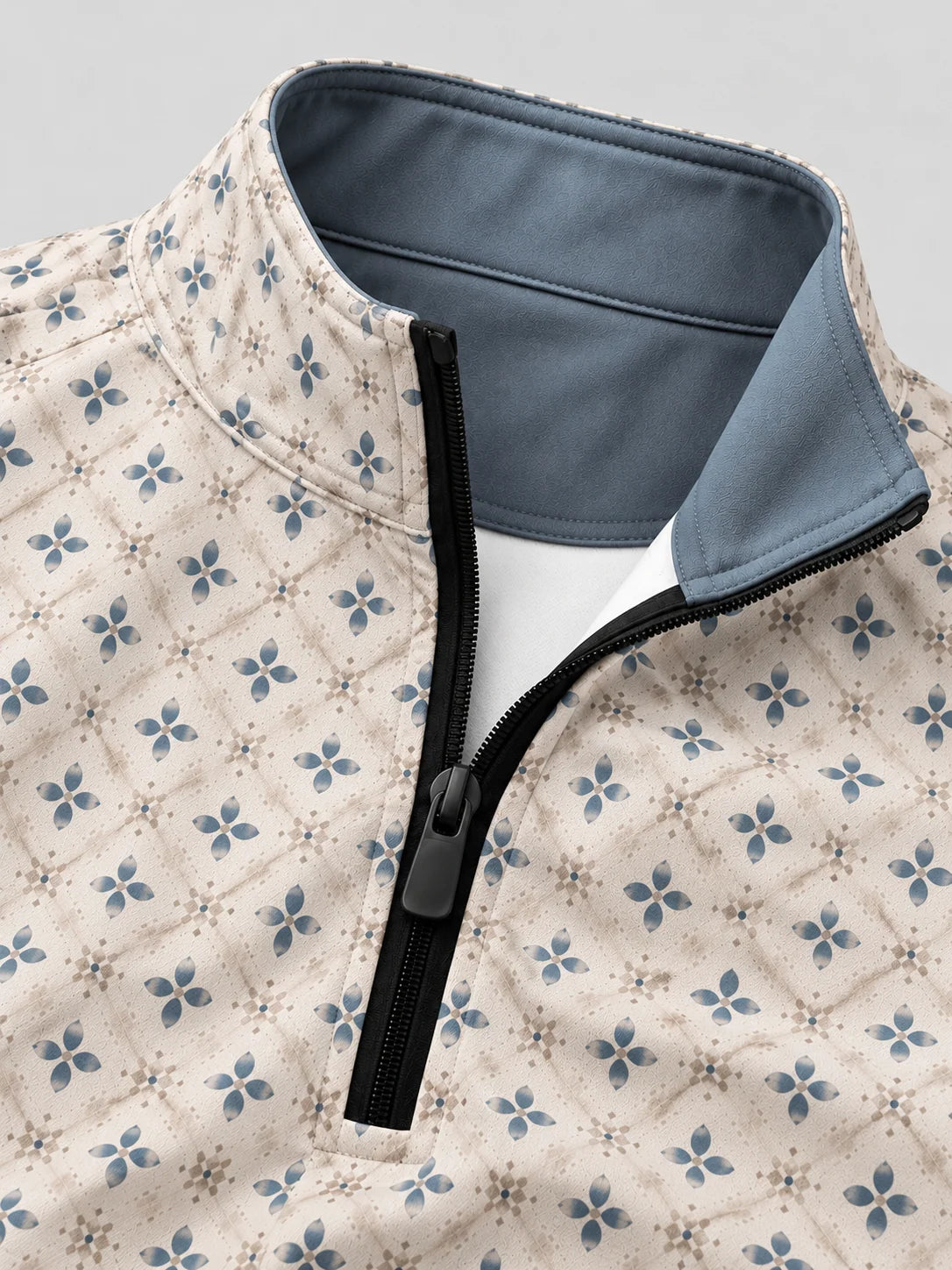 Cremefarbener Golfpullover aus Funktionsmaterial mit blauem Blumenmuster und kurzem Reißverschluss